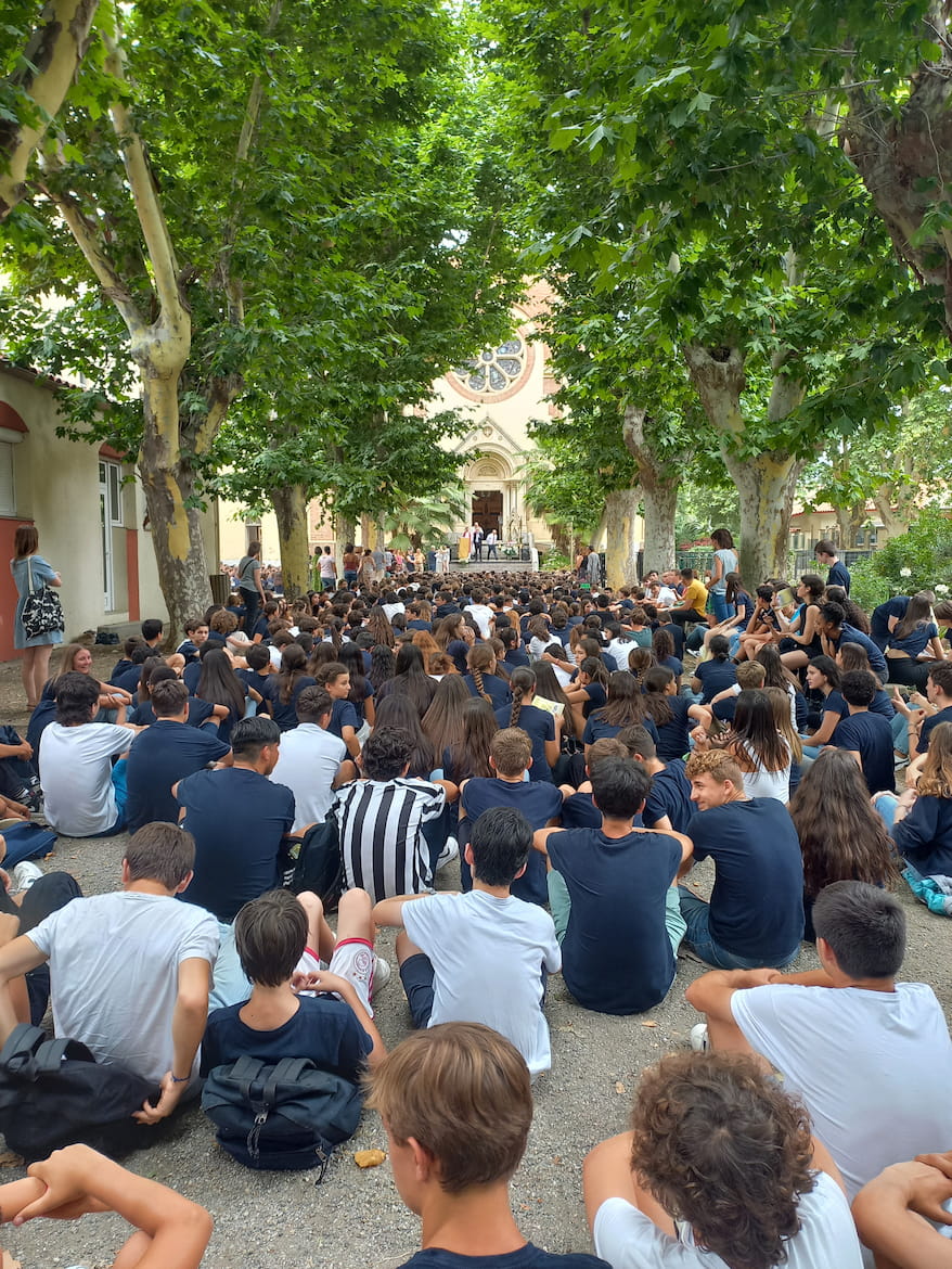 Elèves assis dans la cour pour une cérémonie catholique à l'Institution Saint-Louis de Gonzague