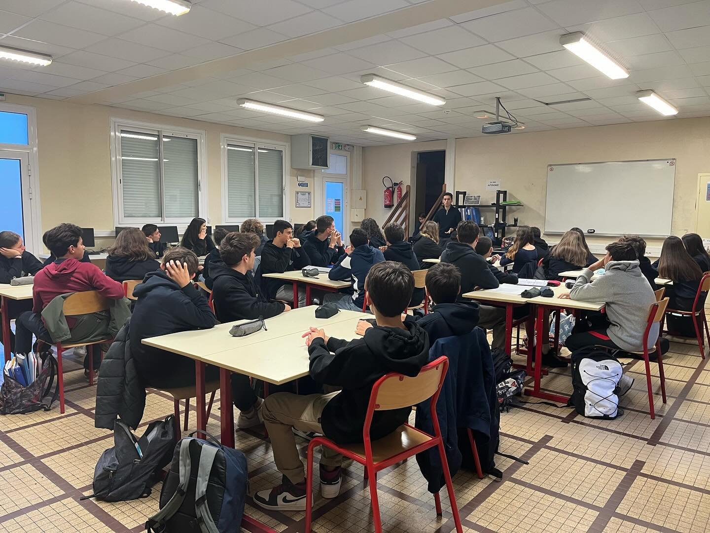 Collégiens assis dans des fauteuils, en train de lire un livre